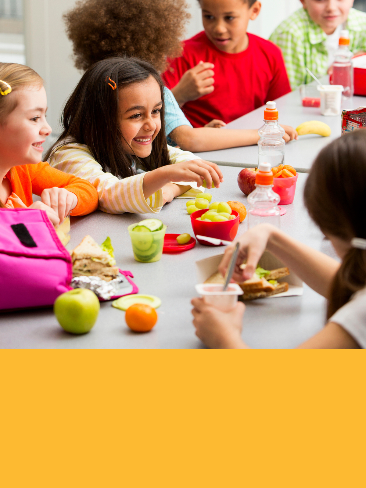 Children sitting at a table at school and enjoy their healthy lunches together